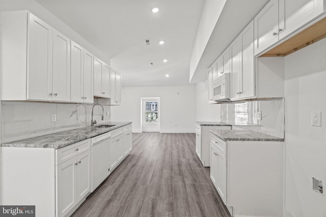 kitchen featuring white appliances, tasteful backsplash, white cabinetry, and hardwood / wood-style floors