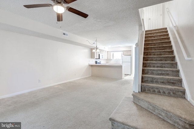 stairs featuring a textured ceiling, carpet, and ceiling fan