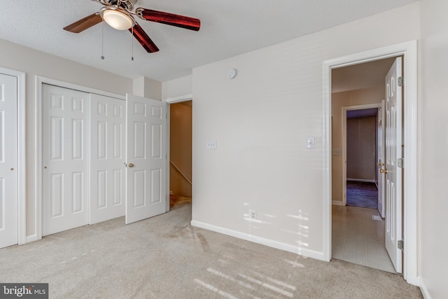 unfurnished bedroom with light carpet, a textured ceiling, and ceiling fan