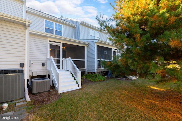 back of house featuring central AC unit, a lawn, and a sunroom