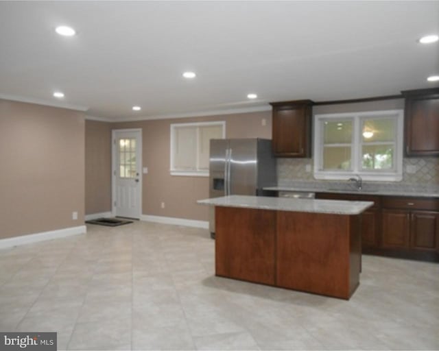 kitchen with crown molding, tasteful backsplash, light tile flooring, a kitchen island, and sink