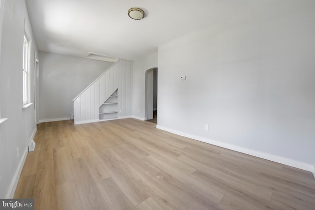 unfurnished living room featuring built in features and light hardwood / wood-style floors