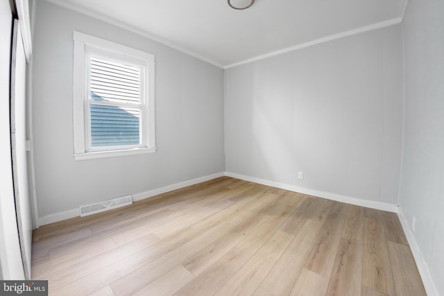 empty room with ornamental molding and light wood-type flooring