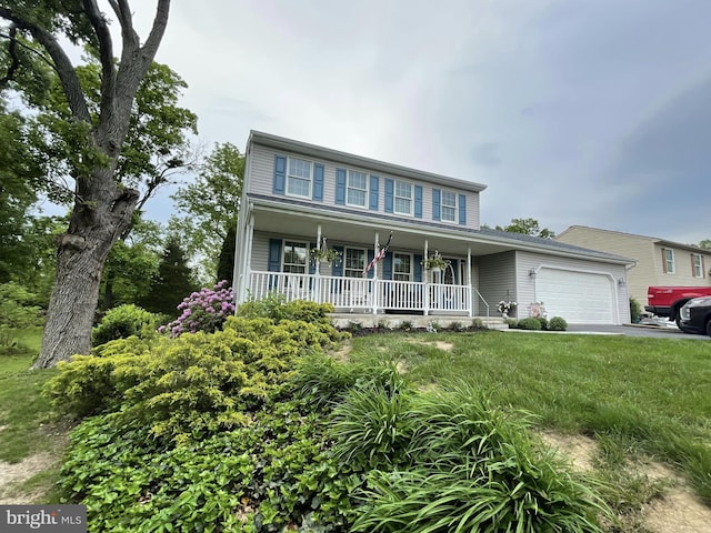 view of front of property with covered porch, a front yard, and a garage