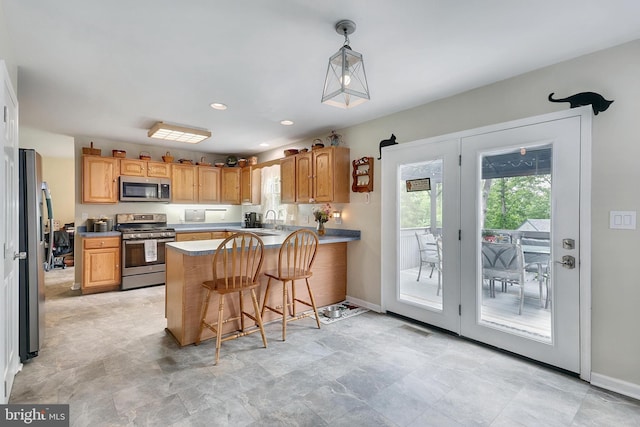 kitchen featuring sink, kitchen peninsula, pendant lighting, a breakfast bar, and appliances with stainless steel finishes