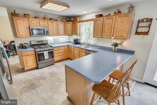 kitchen with a breakfast bar, appliances with stainless steel finishes, kitchen peninsula, and sink