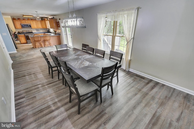 dining area with hardwood / wood-style floors and an inviting chandelier