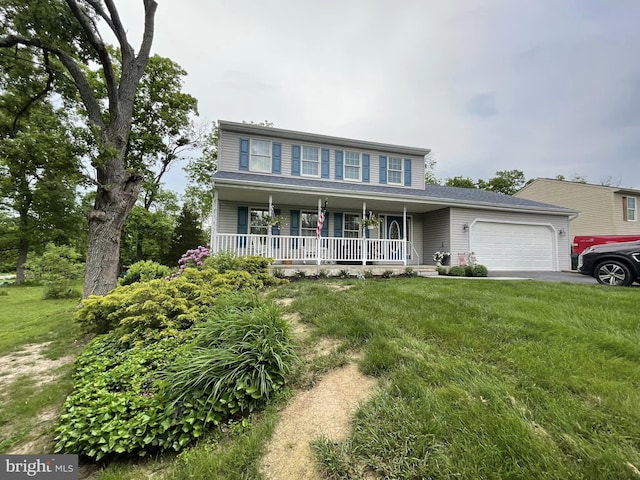 view of front of house with covered porch, a garage, and a front yard