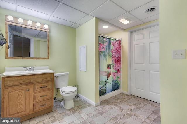 bathroom featuring a paneled ceiling, curtained shower, vanity, and toilet