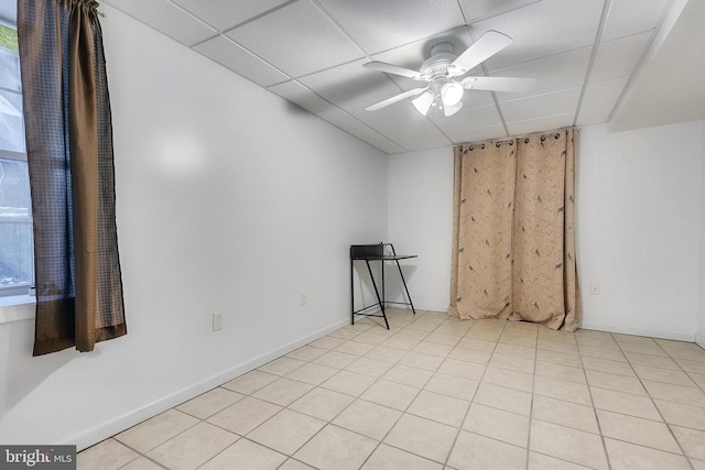 empty room with a drop ceiling, ceiling fan, and light tile patterned floors