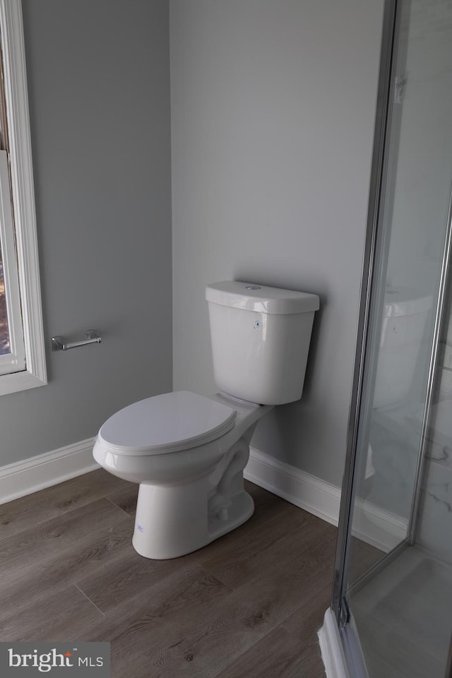 bathroom with a shower with shower door, hardwood / wood-style floors, and toilet