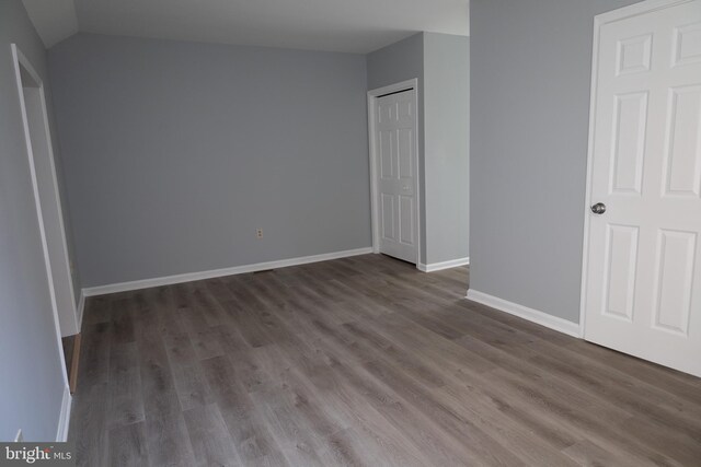 unfurnished bedroom featuring dark hardwood / wood-style floors, a closet, and vaulted ceiling