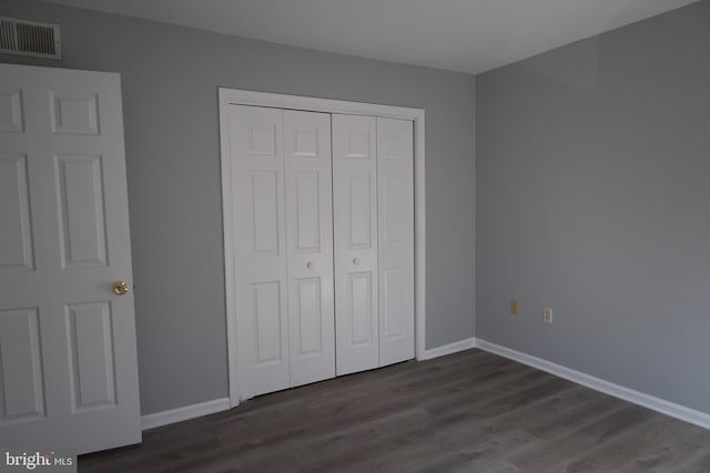 unfurnished bedroom featuring a closet and dark wood-type flooring