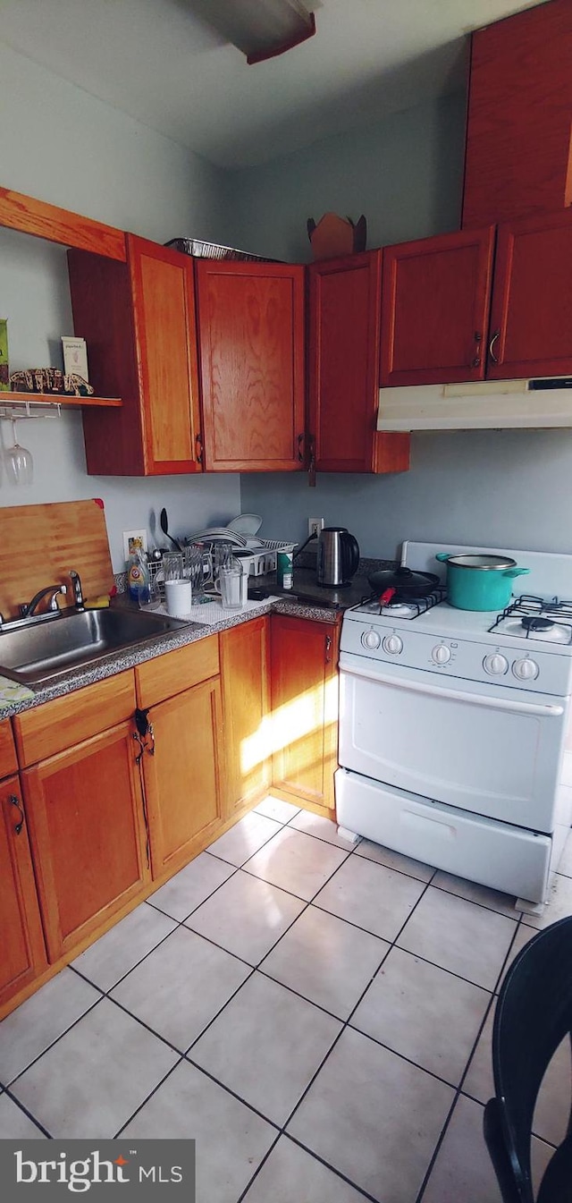 kitchen with gas range gas stove, sink, and light tile floors