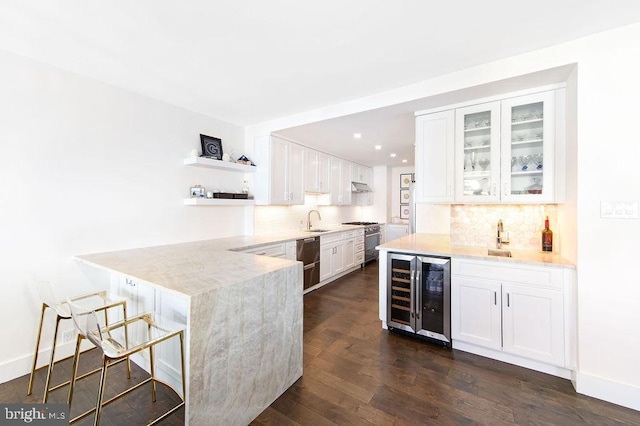 kitchen with stainless steel range, dark wood-type flooring, wine cooler, a breakfast bar area, and white cabinets