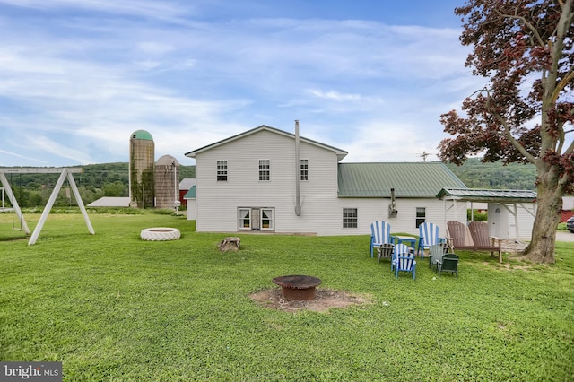 rear view of property with an outdoor fire pit and a yard