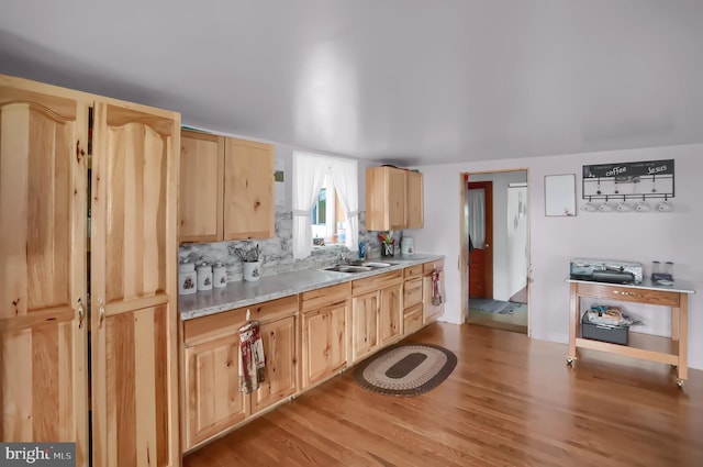 kitchen featuring sink, light brown cabinetry, tasteful backsplash, and light wood-type flooring