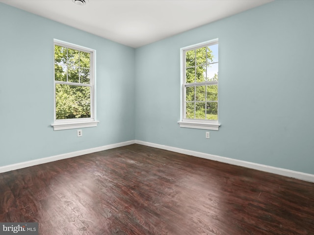 unfurnished room with plenty of natural light and dark wood-type flooring