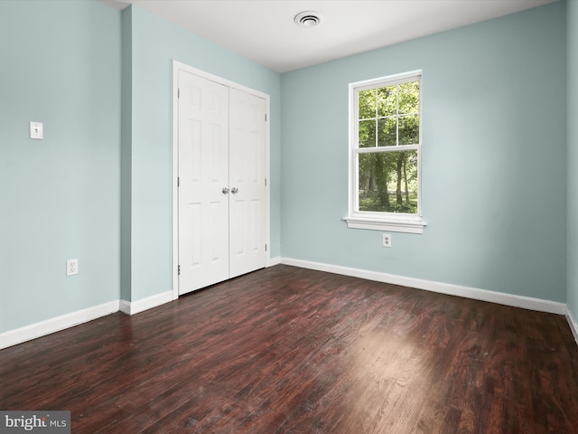 unfurnished bedroom featuring a closet and dark hardwood / wood-style flooring