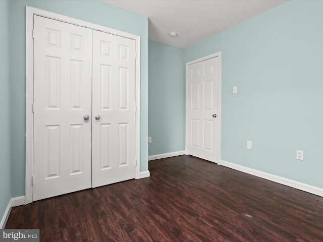 unfurnished bedroom featuring dark wood-type flooring and a closet