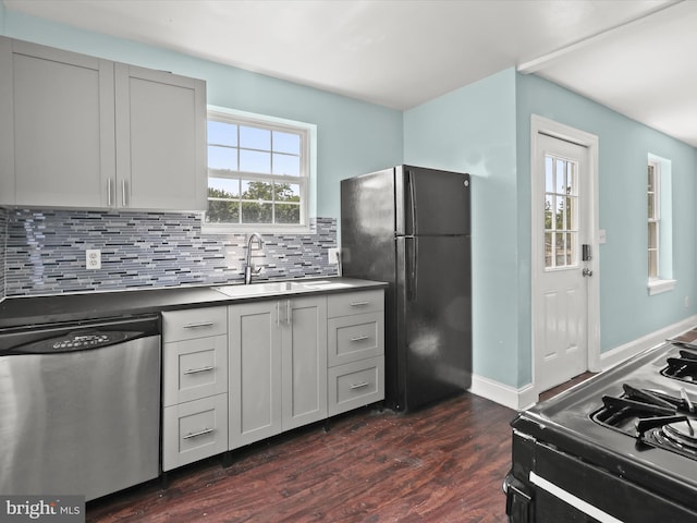 kitchen with stove, black refrigerator, sink, stainless steel dishwasher, and dark hardwood / wood-style flooring