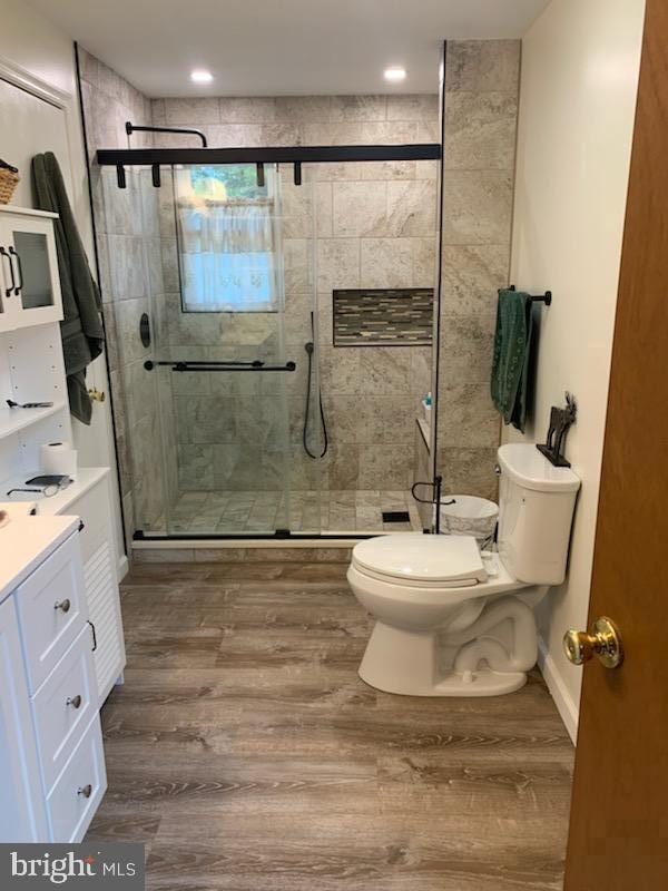 bathroom with vanity, hardwood / wood-style floors, walk in shower, and toilet