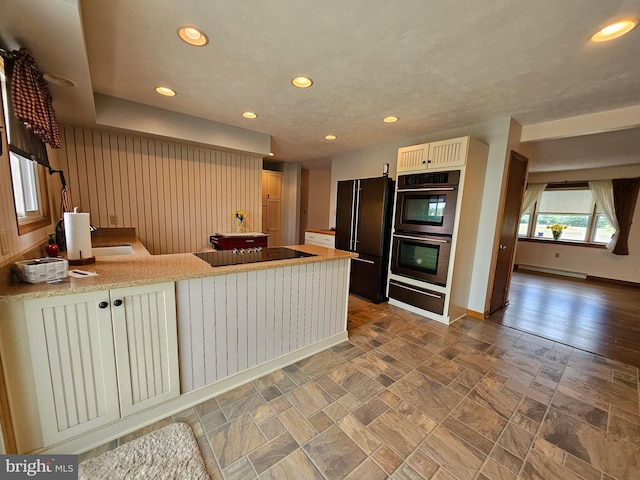 kitchen featuring baseboard heating, black appliances, and kitchen peninsula