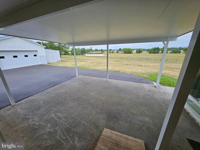 view of patio / terrace featuring a rural view, a garage, and an outdoor structure