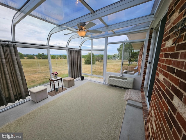 unfurnished sunroom featuring ceiling fan, a wall unit AC, and plenty of natural light