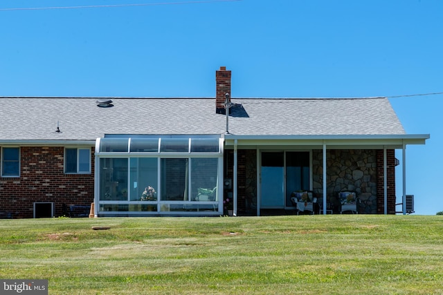 rear view of house featuring a lawn and a sunroom