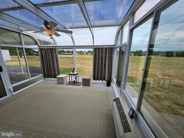 unfurnished sunroom with ceiling fan, a rural view, and plenty of natural light