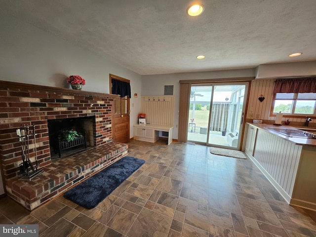 unfurnished living room featuring a textured ceiling, a healthy amount of sunlight, and a fireplace