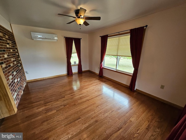 spare room featuring ceiling fan, a wall mounted AC, and wood-type flooring