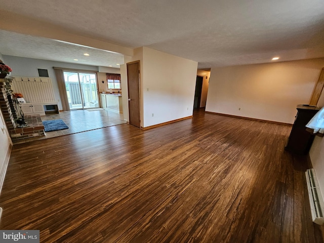 unfurnished living room featuring a fireplace, baseboard heating, a textured ceiling, and dark wood-type flooring