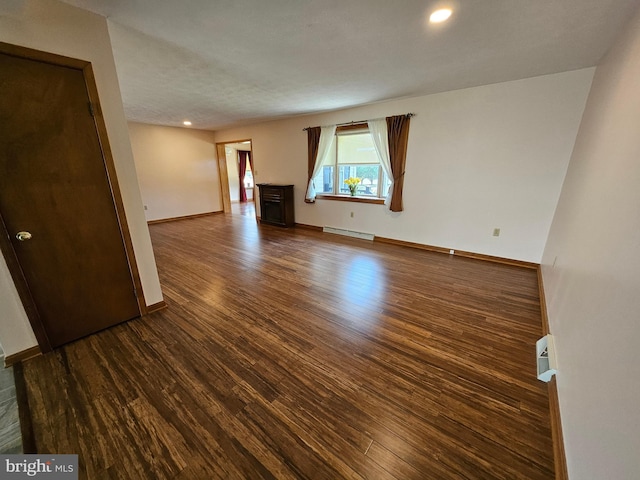 unfurnished room featuring dark hardwood / wood-style flooring and a baseboard heating unit