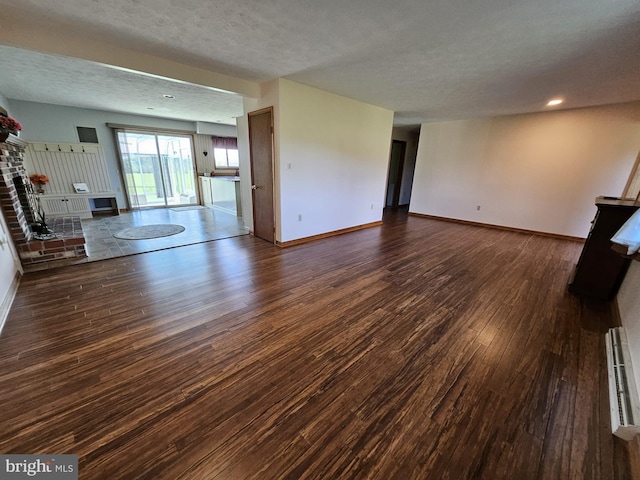 unfurnished living room featuring dark wood-type flooring, a textured ceiling, a fireplace, and baseboard heating