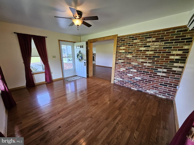 unfurnished room featuring brick wall, dark hardwood / wood-style flooring, and ceiling fan