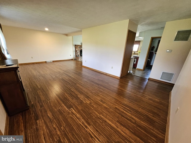 unfurnished living room featuring a brick fireplace and dark hardwood / wood-style floors