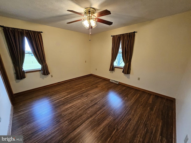 empty room featuring a textured ceiling, ceiling fan, and dark hardwood / wood-style floors