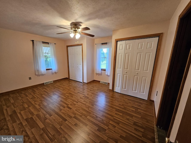 unfurnished bedroom featuring multiple windows, multiple closets, ceiling fan, and dark hardwood / wood-style floors