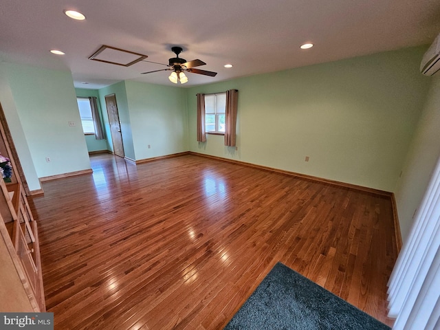 spare room featuring ceiling fan, a wall mounted AC, and wood-type flooring