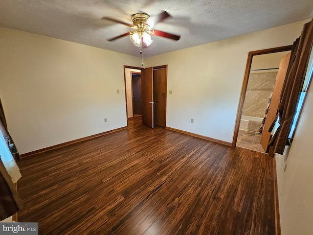 unfurnished bedroom featuring ensuite bath, a textured ceiling, ceiling fan, and dark hardwood / wood-style flooring