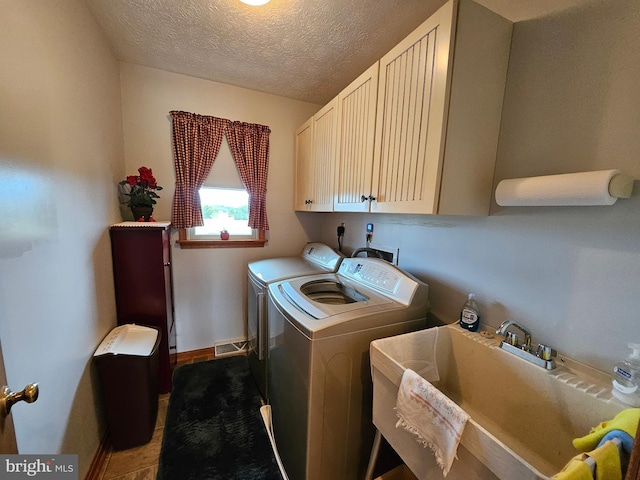 laundry room featuring sink, washer and clothes dryer, a textured ceiling, and cabinets