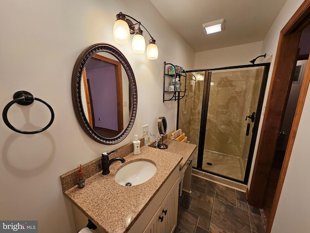 bathroom featuring a shower with door and vanity