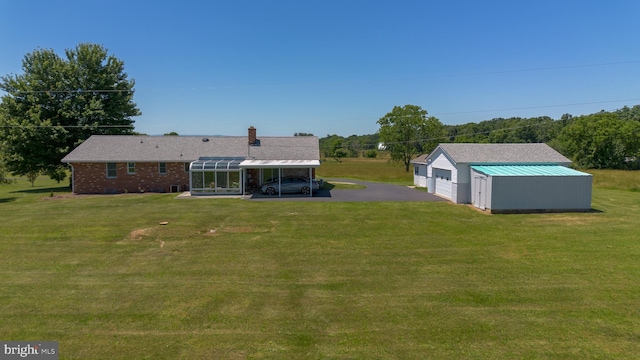 rear view of property with a garage, a lawn, a carport, and an outdoor structure