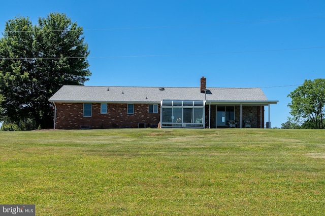 rear view of house with a yard and a sunroom