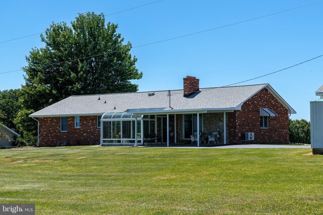 rear view of house with a sunroom and a lawn