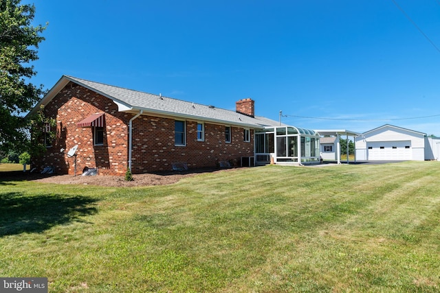 back of property with a sunroom, a yard, and a garage