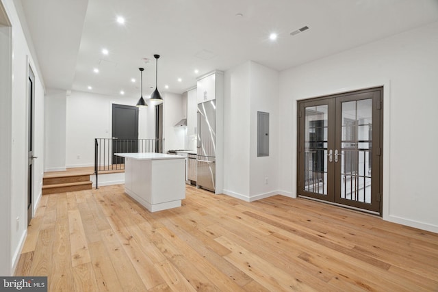 kitchen with french doors, hanging light fixtures, white cabinetry, a kitchen island, and electric panel