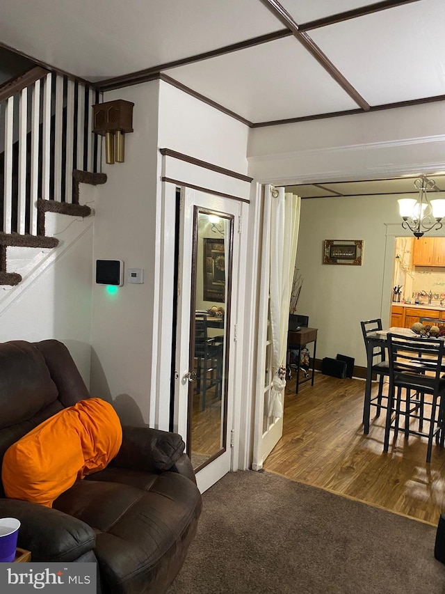 living room with hardwood / wood-style floors, ornamental molding, and a chandelier